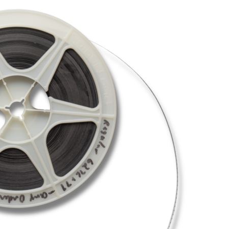 A reel of black magnetic tape, partially unwound, on a white plastic spool with handwritten text along the edge, evokes themes of emotional healing against a black background.